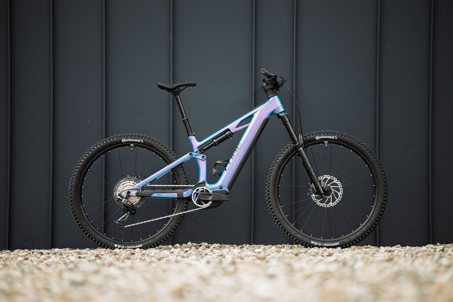 Polnovzmeteno električno gorsko kolo CUBE Stereo Hybrid ONE44 HPC SLX v prelivajoči se barvi dream 'n' black, slikano zunaj pred ograjo